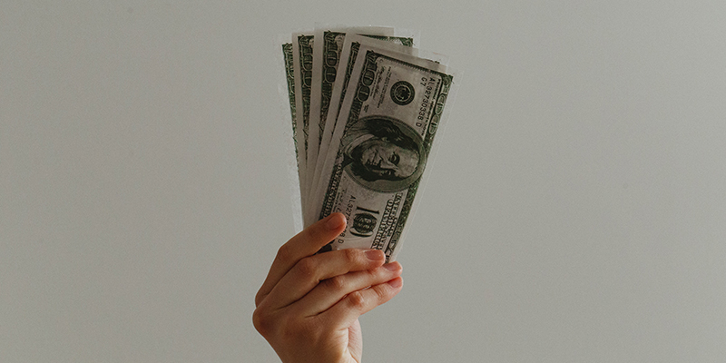 Hand holding stack of dollar bills