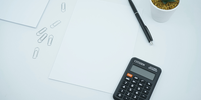 Calculator pen plain sheet and clips on a white desk