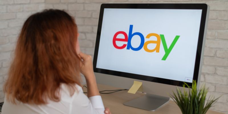 Woman looking at the Ebay logo on a computer monitor