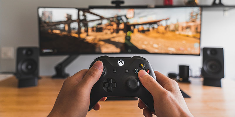 Man holding a controller and playing video games on a large screen