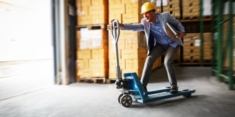 Man smiling while riding on a pallet jack