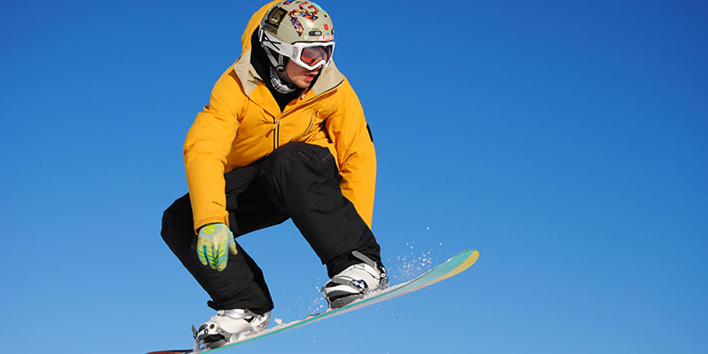 Person wearing a yellow jacket and black snow pants snowboarding 