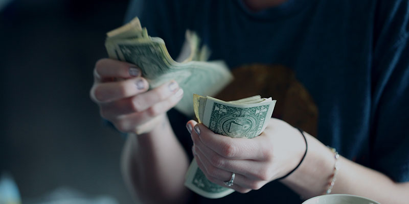 A young woman counting dollar bills