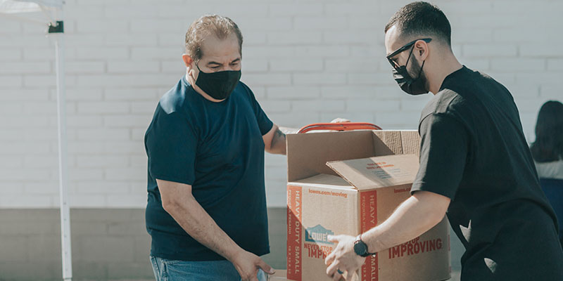 Two men dressed in black tshirts packaging boxes