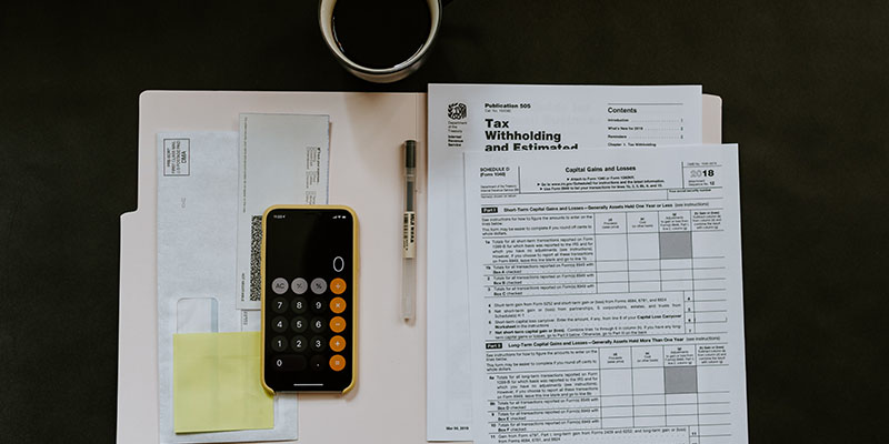 Black Andoird smartphone, pen and tax withholding certificate on a table