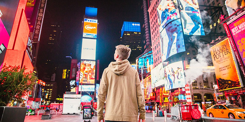 Man standing at the TimeSquare and staring at digital screens