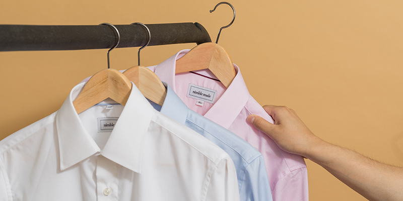 A hand picking a pink shirt from the rack.