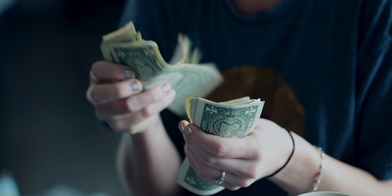 A twenty-four year old woman counting dollar bills.