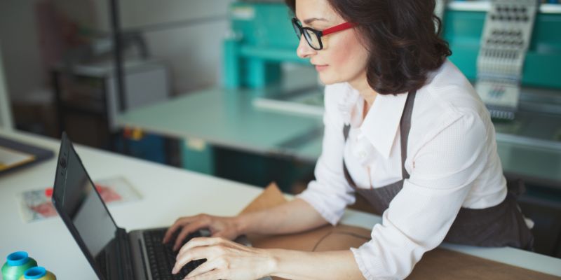 Woman leaning on a counter using a laptop