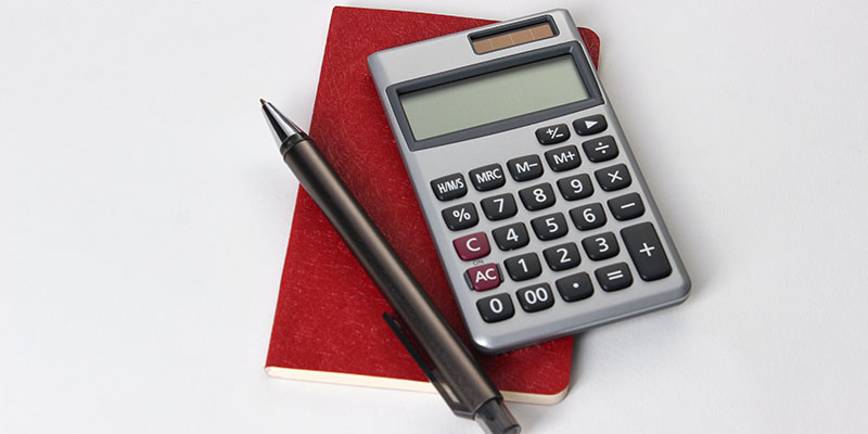 A notebook, pen, and calculator on a white table