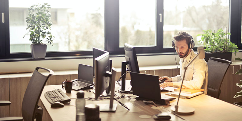 Man with headphones facing computer screen