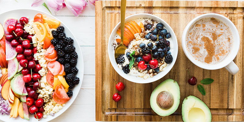 A plate and two bowls full of berries and fruits