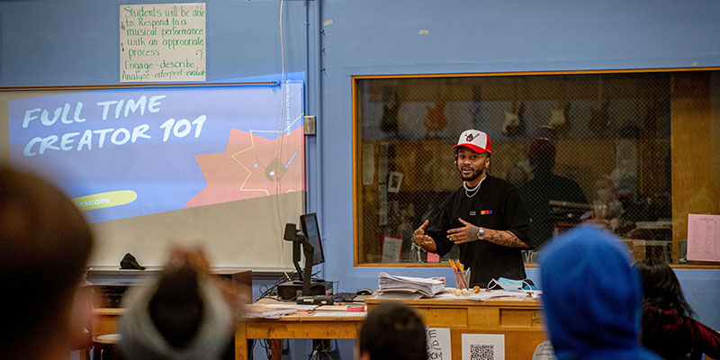 A man giving a lecture on "Creator 101" to students in a class
