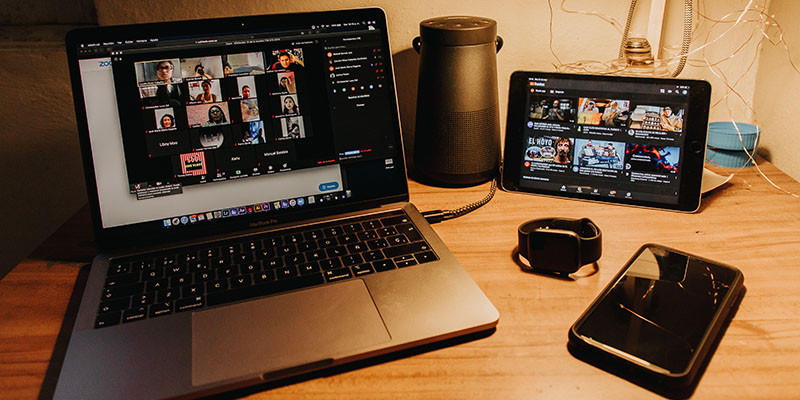 A laptop, tab, and watch on a brown desk