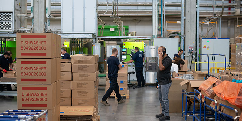 A busy warehouse with cartons and employees doing work