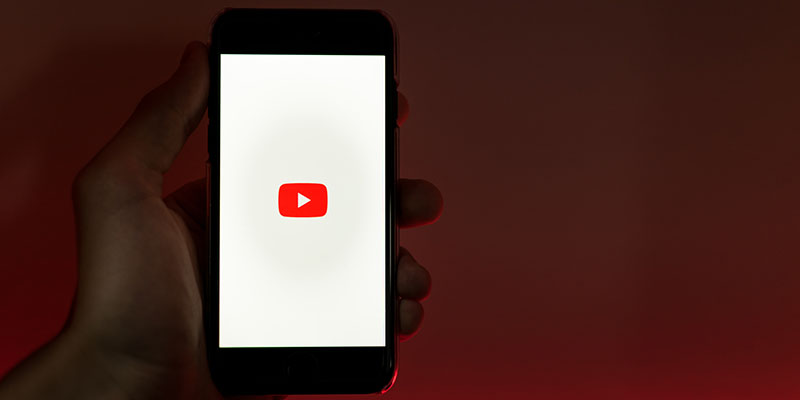 A hand holding a mobile with YouTube logo on its screen