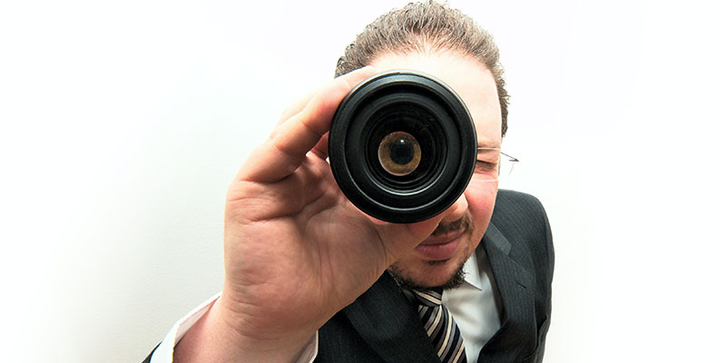 A man in a suit looking through a binocular