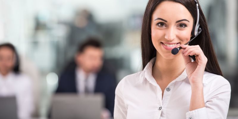 call center rep wearing headset with other reps sitting in the background