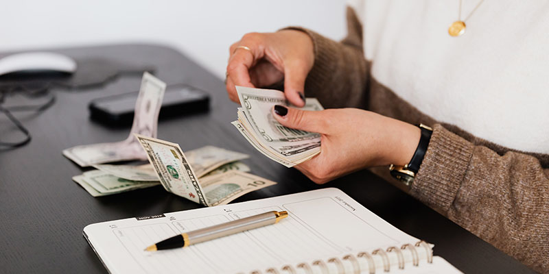 A lady counting cash money on her desk.