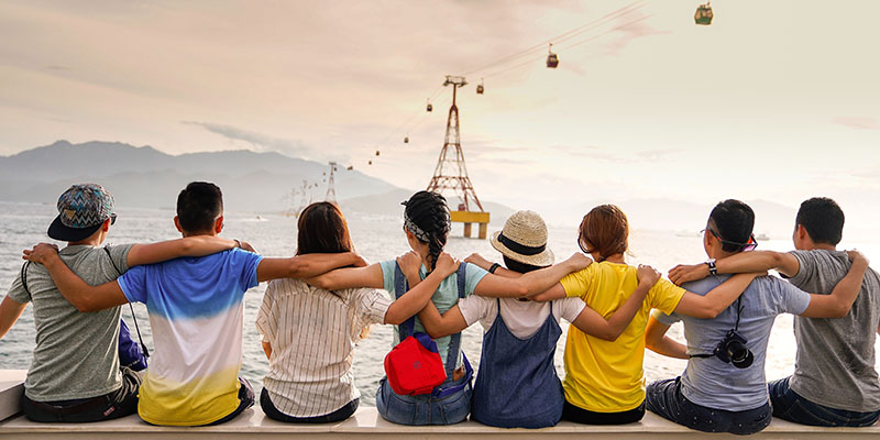 A group of eight youngsters sitting by a scenic place