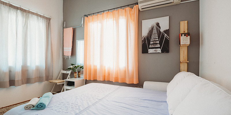 A clean room with orange screens and white bed