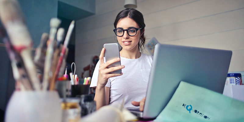 A specs-wearing young woman scrolling on a phone