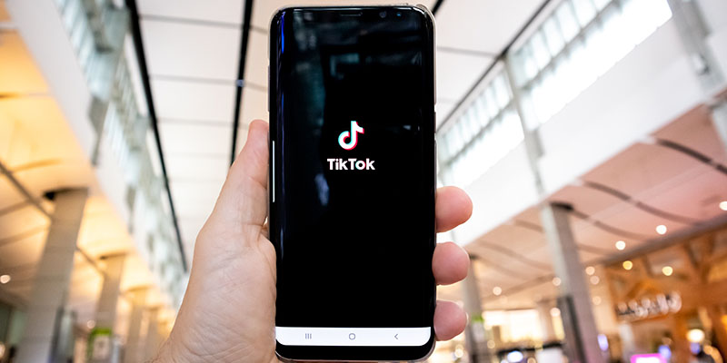 A hand showing a phone with a TikTok app 
