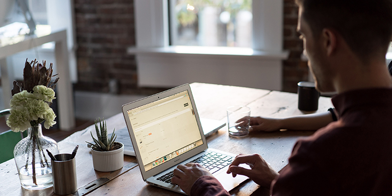 A sideways shot of a man working on his laptop