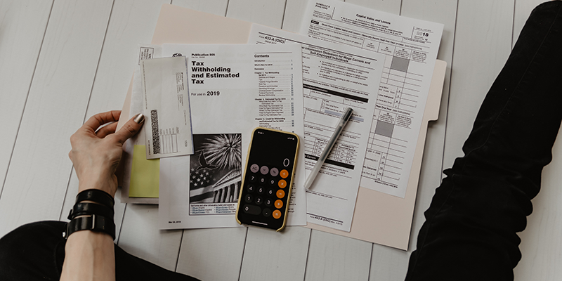 Different taxation forms, a pen, and a calculator on a White wooden platform