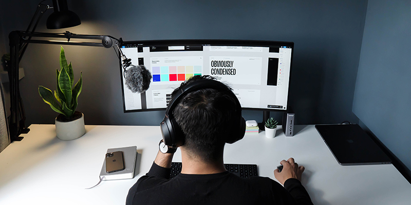 A man facing computer desk setup working for a client