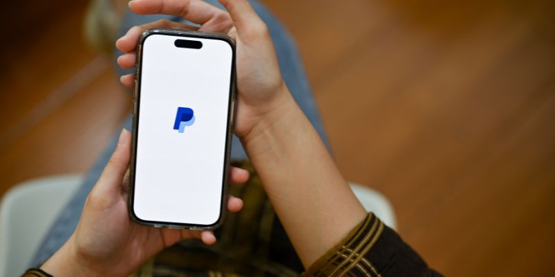 hands holding a smartphone with a paypal logo