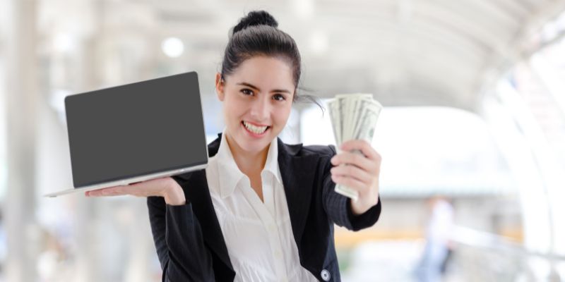 woman holding a laptop and cash