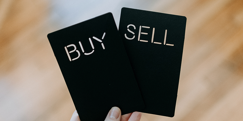Two black cards that read buy and sell