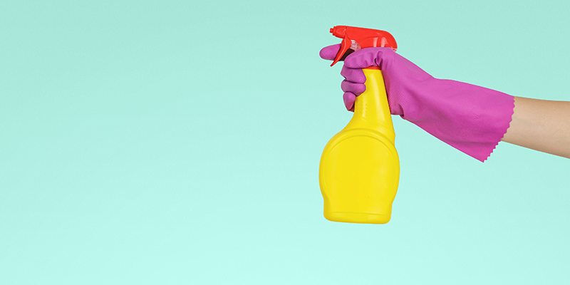 A hand wearing a Pink glove and usiing a spray bottle