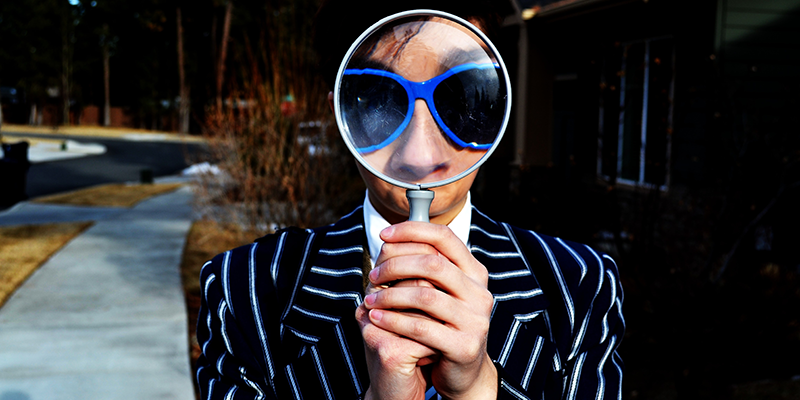 A man wearing a striped suit holding a magnifying glass