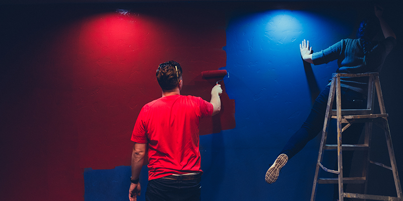 A man and a woman painting a blue wall red