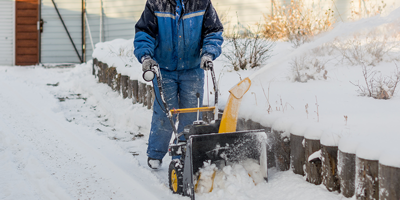 A man shoveling snow with a snow blower