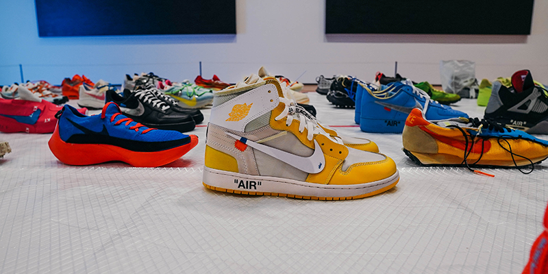 Multiple sneakers arranged in a line on a White table