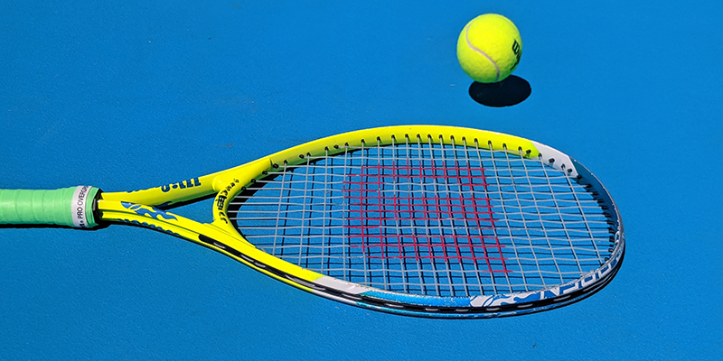 Tennis racket and ball on a blue court