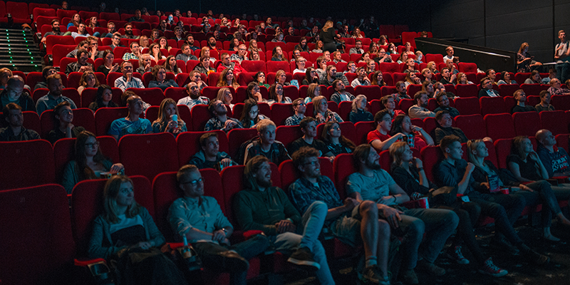 A movie theatre with full of people watching a movie