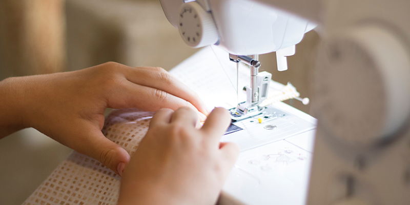 A child's hands guiding a fabric on a sewing machine.