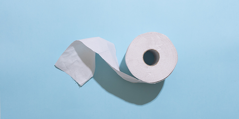 A roll of toilet paper against a blue backdrop