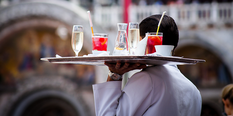 A waiter carrying a plate full of drinks