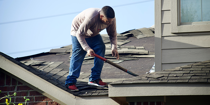 Roofer tearing the roof apart before installing a brand new roof